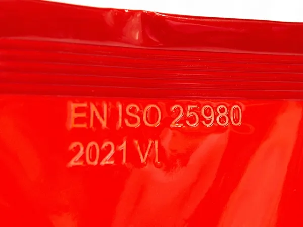 Powiększenie numeru normy EN ISO 25980 na czerwonej zasłonie spawalniczej z elastycznej folii PCV, zapewniającej ochronę przed promieniowaniem UV i IR.